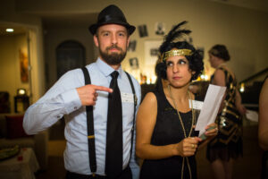 Night of Mystery | How To Play Murder Mystery Game Candid moment of guests solving clues at a 1920s murder mystery party