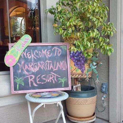 Chalkboard sign reading "Welcome to Margaritaland Resort" with decorations at a Margaritaland murder mystery party.
