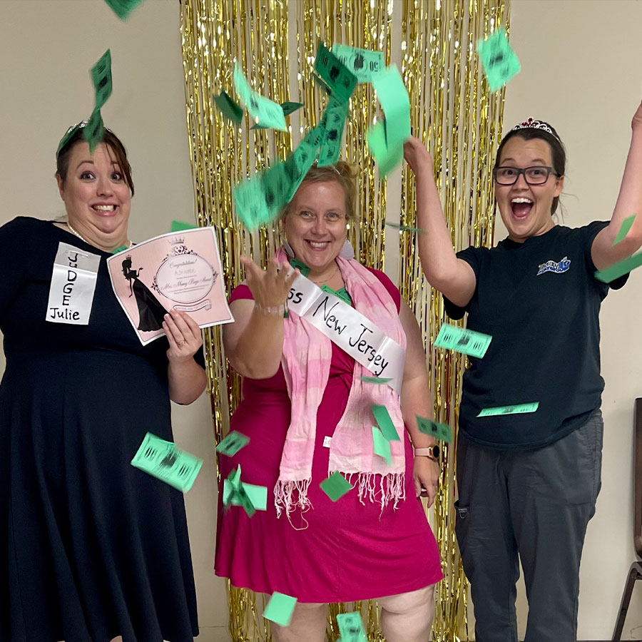 Participants in costume for a pageant-themed murder mystery party, throwing money in celebration.