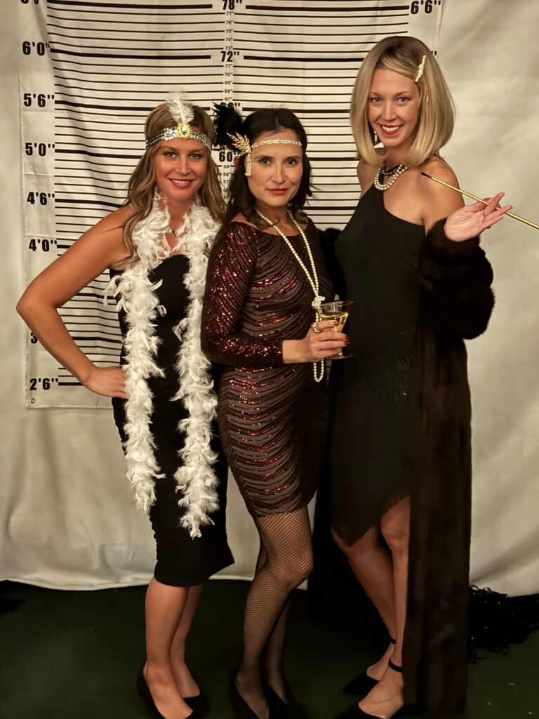 Three female in a flapper dress with a mugshot background