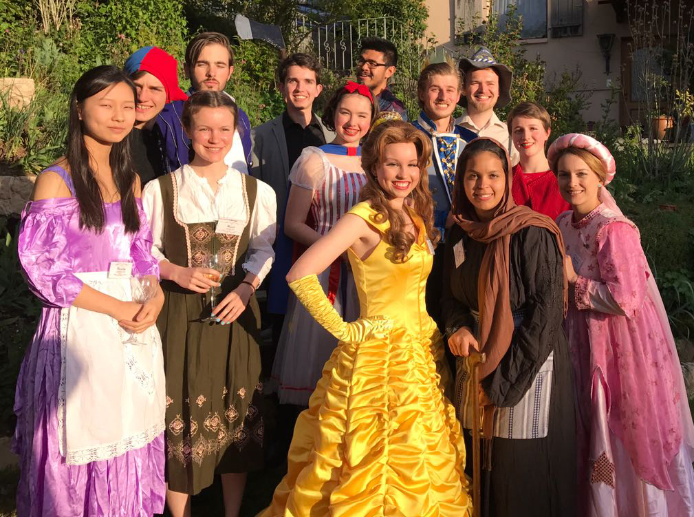 Guests enjoying a springtime murder mystery party outdoors with festive decorations and costumes.
