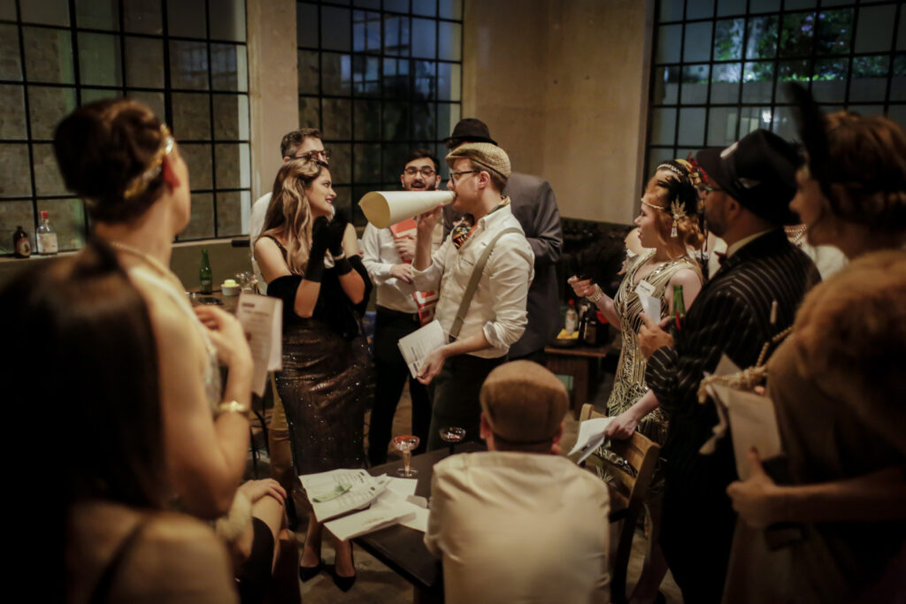 Adults dressed in costumes acting out characters during a Friendsgiving murder mystery party.