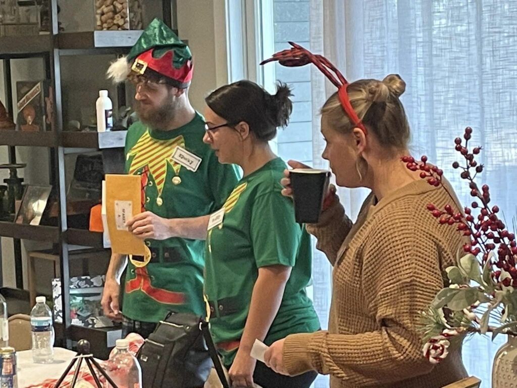 Coworkers interacting and sleuthing during a holiday murder mystery at a corporate office party.