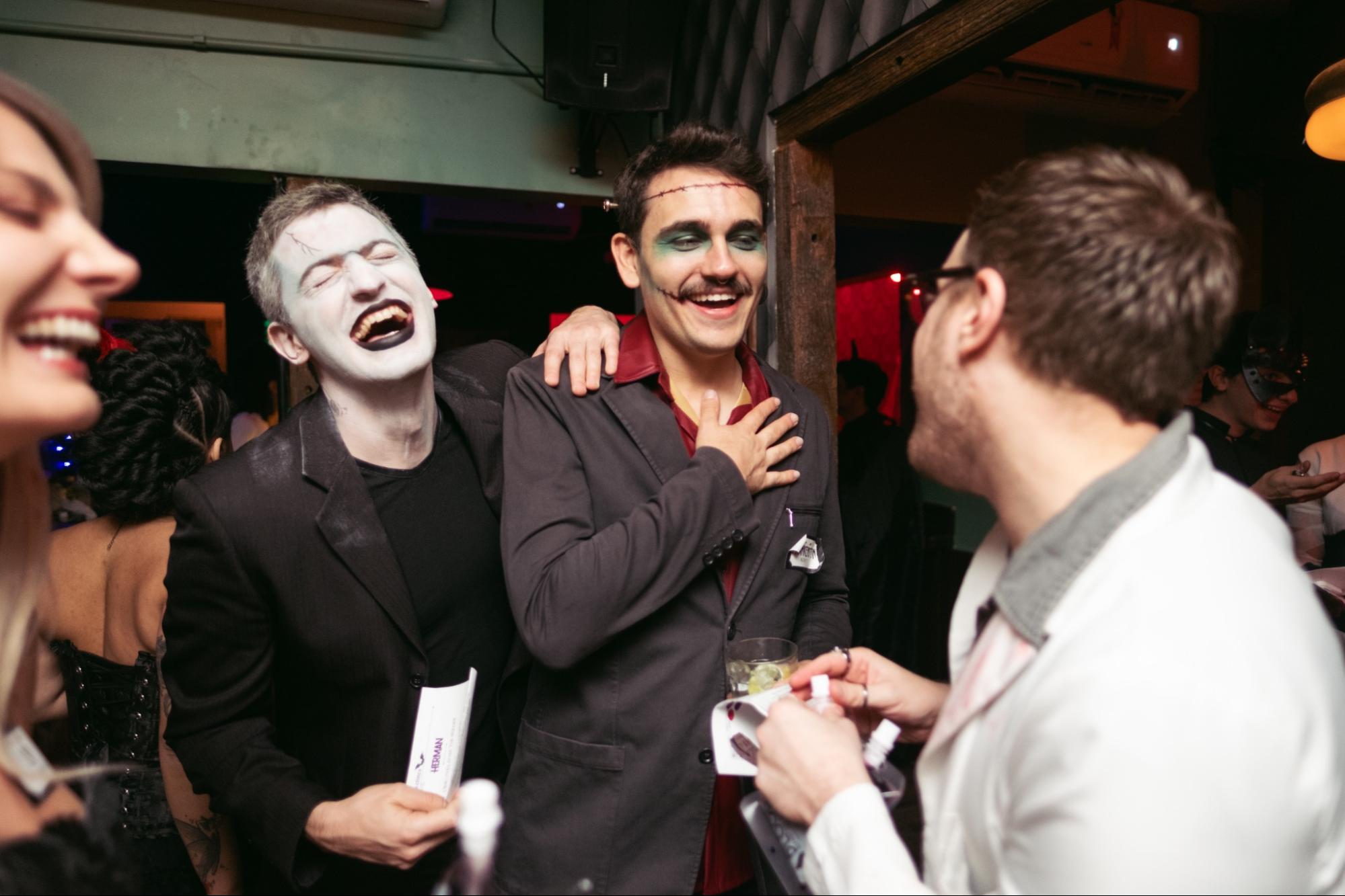 Guests in Halloween costumes solving clues at a murder mystery party with spooky decorations