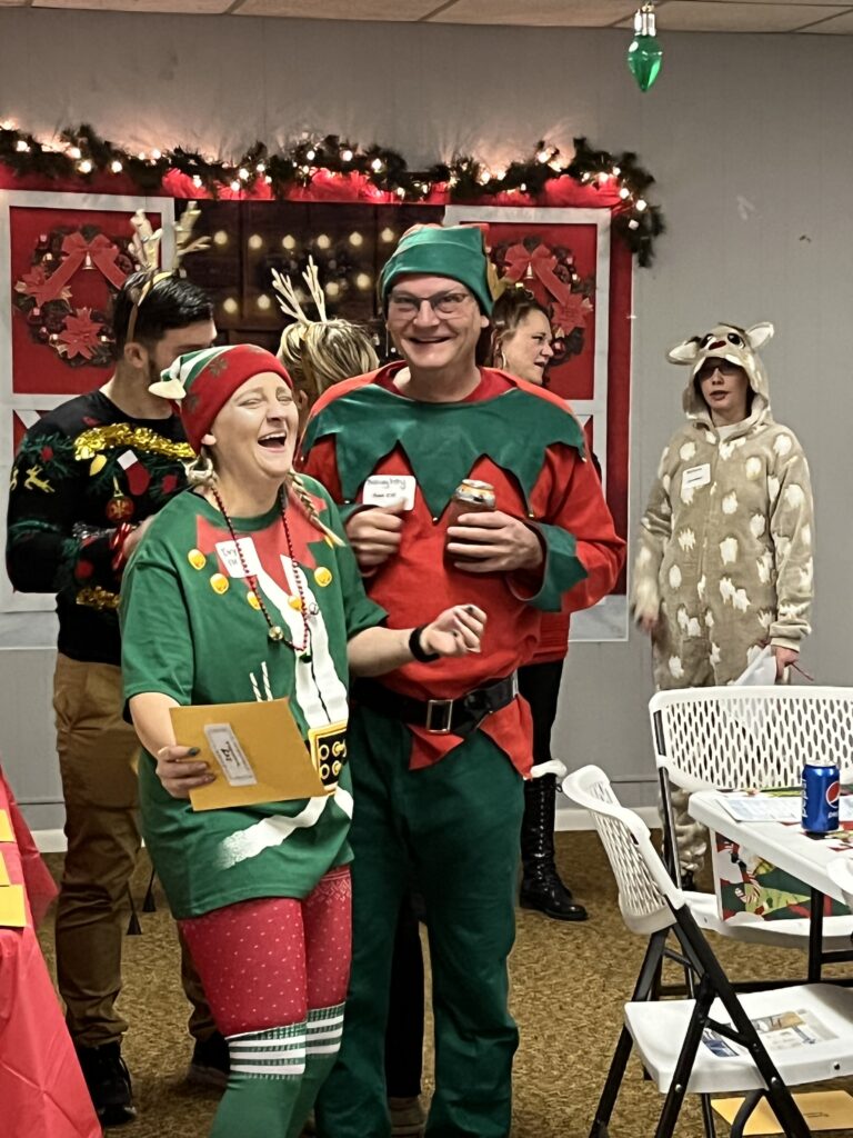 Guests in festive costumes posing with props at a Christmas mystery party.