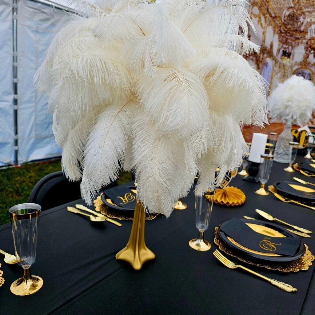 Candlelit masquerade party table with feathers, gold, and mask centerpieces.
