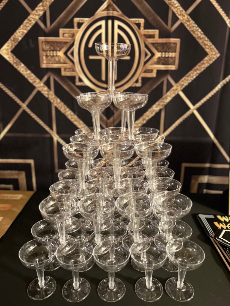 Supplies needed to make a champagne tower including coupe glasses and champagne bottles