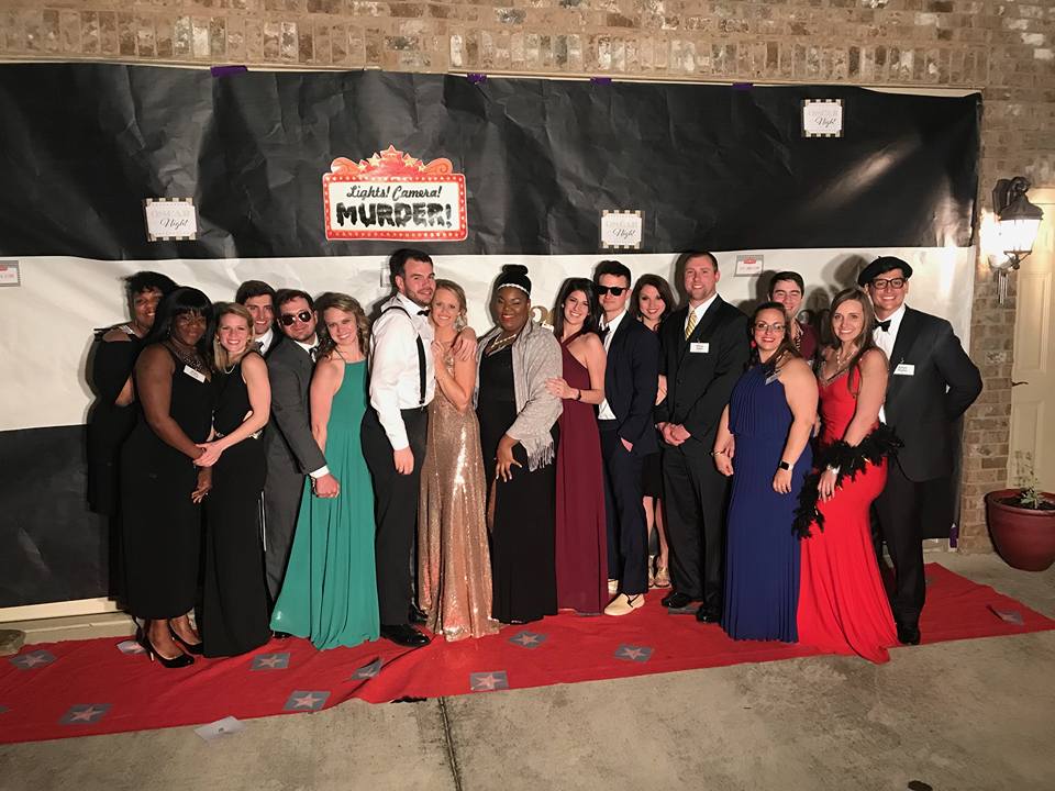 Hollywood murder mystery party guests posing on a red carpet in glamorous attire.