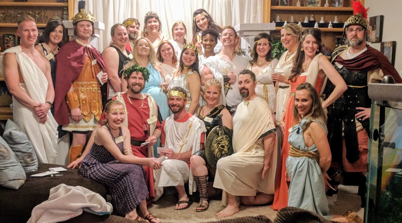Guests in Roman toga costumes posing at a themed murder mystery party.