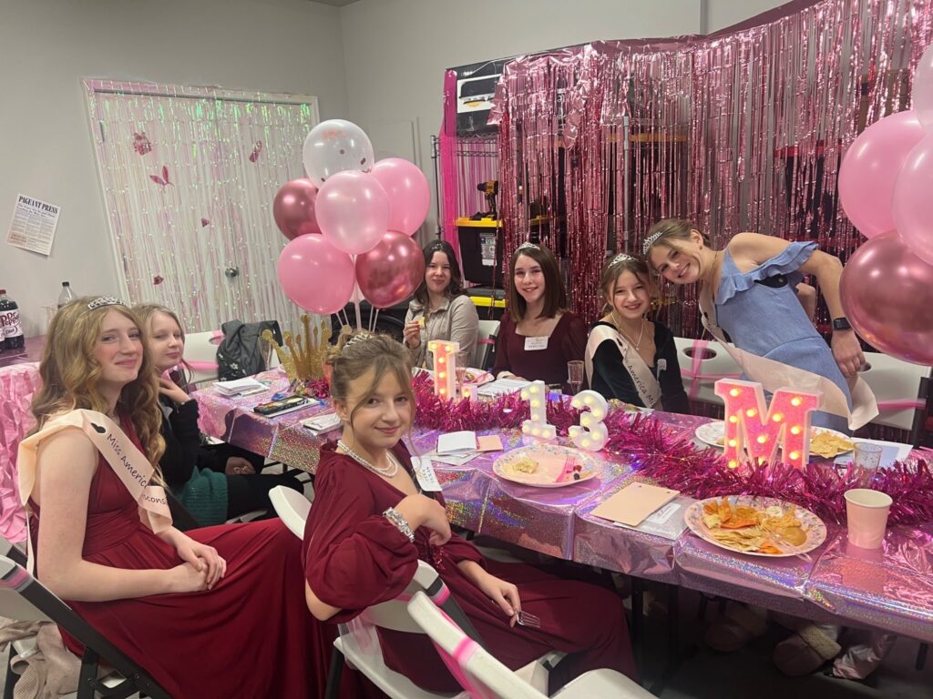Night of Mystery | Sleepover Games For Teens And Tweens That Beat Truth Or Dare A group of young girls celebrating a pageant-themed 13th birthday party around a decorated table.